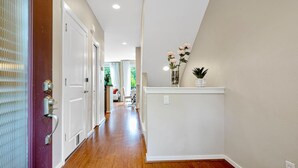 A hallway with wooden flooring, white walls, and a door with a metal handle.