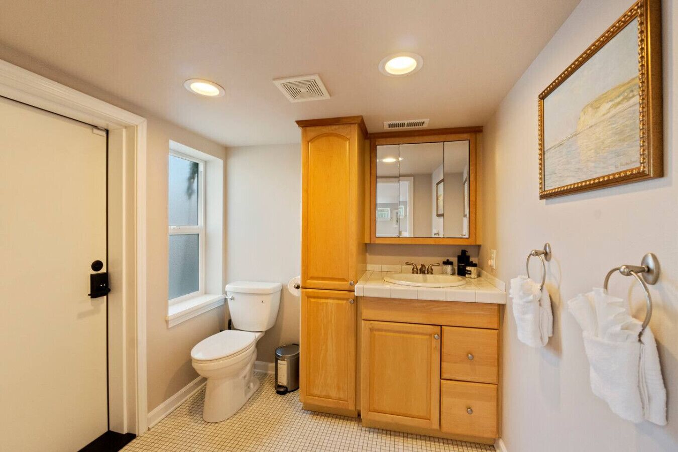 Une salle de bain équipée de toilettes, de meubles en bois, d’un lavabo et d’un miroir.