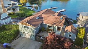 A residential area with a house featuring a sloped roof, a dock, and a lake in the background.