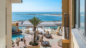 A poolside area with lounge chairs and umbrellas, overlooking a beach and ocean. - Emerald Grande W421 (Destin)