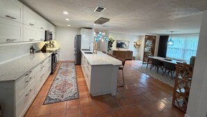Una cocina moderna con armarios blancos, una isla central y un comedor con vistas.