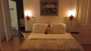 A bedroom with a bed, a painting on the wall, and two bedside lamps.