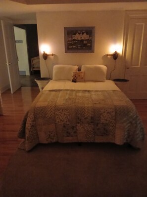Un dormitorio con una cama, un cuadro en la pared y dos lámparas de noche.