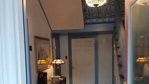 A staircase with a chandelier, a door, a rug, and a small table with a lamp.