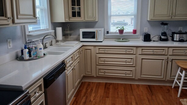 A kitchen with wooden cabinets, a microwave, a sink, and a blender on the counter.