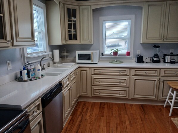 A kitchen with wooden cabinets, a microwave, a sink, and a blender on the counter. - Pink Lady on Main, Downtown Pilot Mtn, business district. Pet Friendly. (Pilot Mtn)