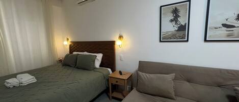 Una habitación de hotel con una cama, un sofá y dos lámparas de pared.