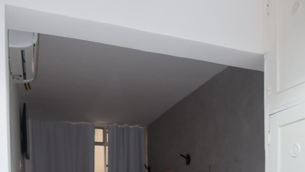 Un dormitorio con cama, una silla, una planta y una escalera.