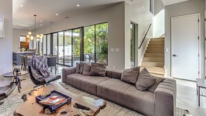 Una sala de estar moderna con sofá, mesa de centro y una escalera que sube a un nivel superior.