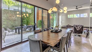 Un comedor espacioso con una gran mesa de madera, sillas de cuero y una lámpara moderna.
