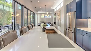 Una cocina moderna con una isla grande, electrodomésticos de acero inoxidable y un comedor con vistas al exterior.