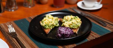 A breakfast setting with toast topped with avocado and a side of red cabbage.