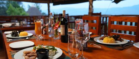 Una mesa de comedor dispuesta con platos de comida, copas de vino y una botella.