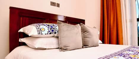 Una cama bien hecha con una colcha estampada y varias almohadas.