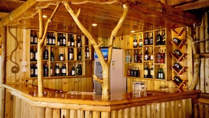 A wooden bar with shelves of bottled beverages and a refrigerator. - Bird Hill Resort Ug (Kabale)