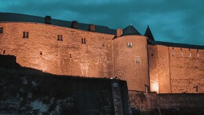 Un mur de pierre ancien, avec une rampe menant à un bâtiment fortifié.