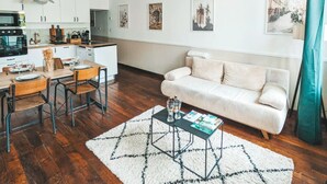 Une cuisine moderne avec des meubles blancs, une table à manger en bois et une table basse noire.