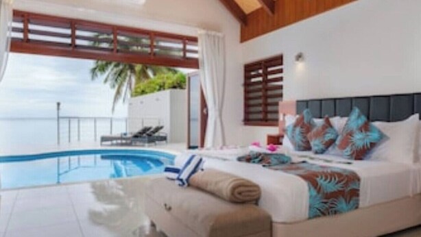 Une chambre avec un grand lit, vue sur la mer et une piscine.