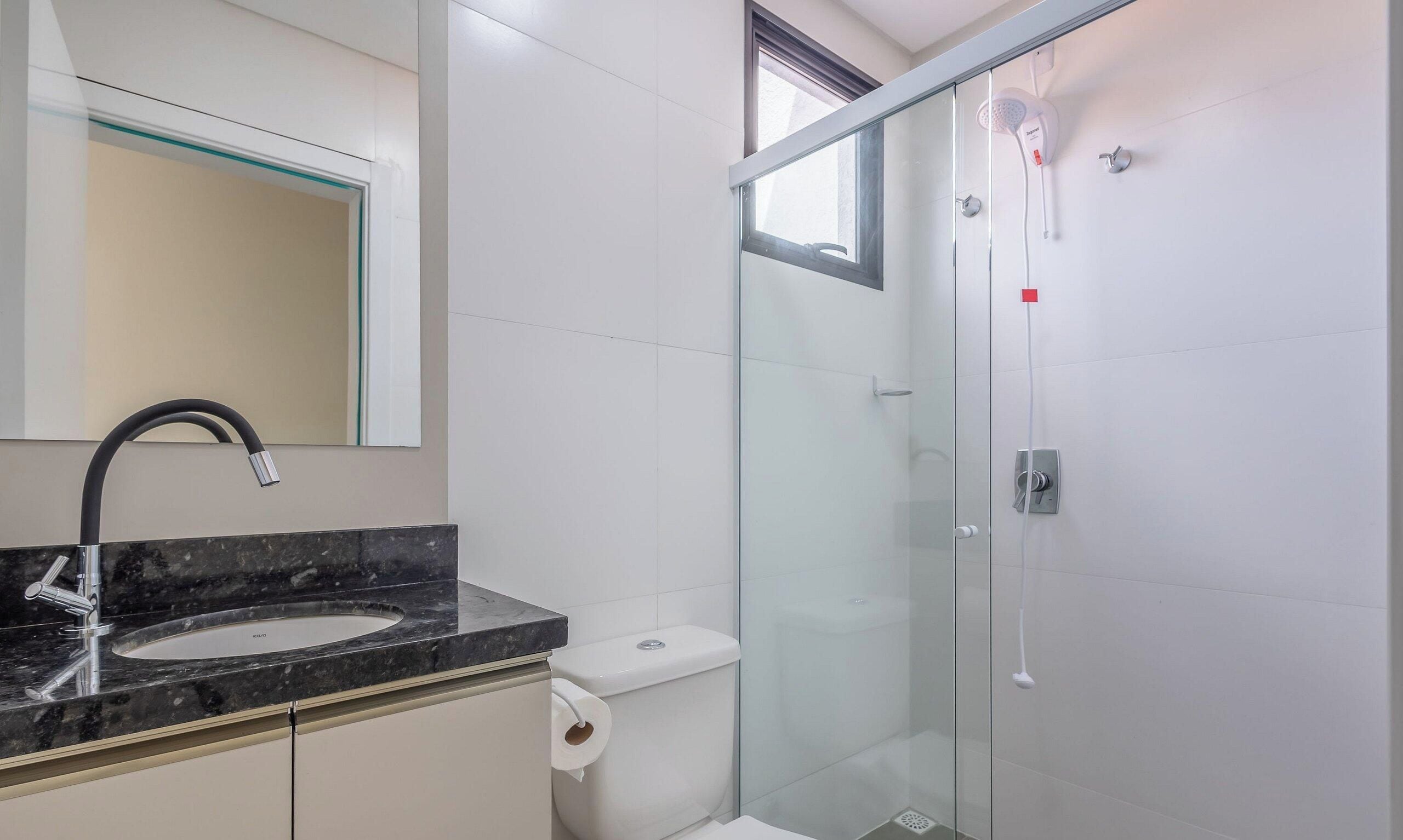 A modern bathroom with a glass shower enclosure, a marble sink, and a toilet.