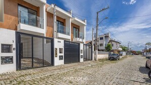 Un immeuble résidentiel moderne doté d’une allée pavée et d’une entrée sécurisée par un portail.