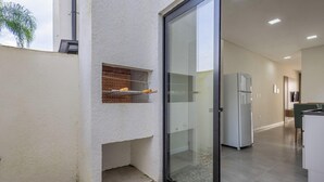 Une cuisine moderne dotée d’un four encastré, d’un réfrigérateur et d’une porte en verre donnant sur un espace extérieur.