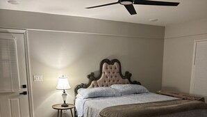 Un dormitorio con cama, ventilador de techo, lámpara y ventana con persianas.