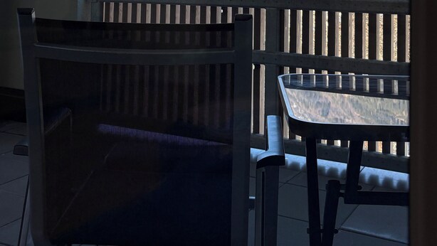 A balcony with a view of snow-capped mountains and a forested valley.