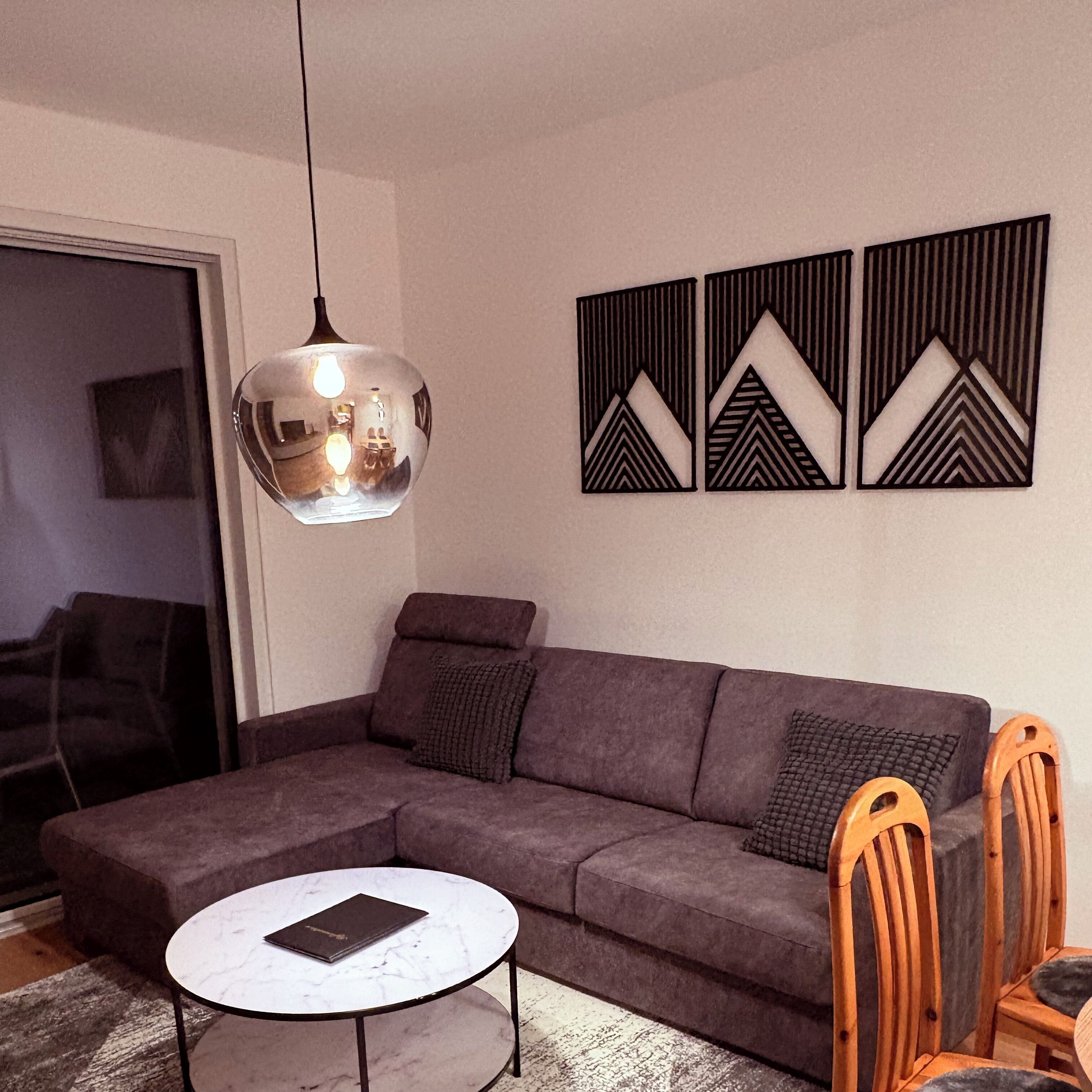 A modern living room with a sectional sofa, a round coffee table, and a pendant light.