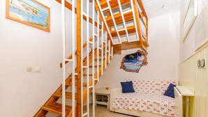 Ein Schlafzimmer mit einer Holztreppe, einem Bett mit Kirschmuster und einem Meeresblick-Gemälde.