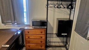 A compact room with a bed, a dresser, a TV, and a window with curtains. - Charming 1-bedroom "glamping" cottage in peaceful Chapin [see description below] (Chapin)