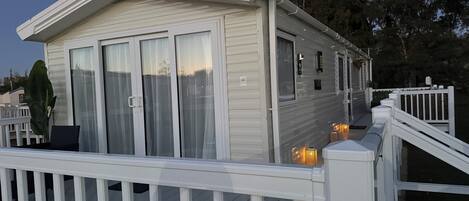 A single-story mobile home with a balcony, white exterior, and a small porch area.