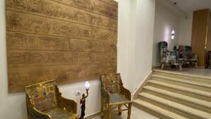 A room with two ornate chairs, a large wall mural, and a staircase leading to another area. - RIWAQ Pyramids Boutique  (Giza)