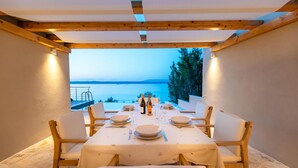 Comedor con una mesa dispuesta para seis personas, con vista a un cuerpo de agua.