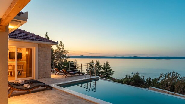 Un área de piscina con sillones de descanso y vista al mar.