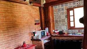 A rustic kitchen with a brick wall, wooden ceiling, and a window. - La Domita (Camanducaia)