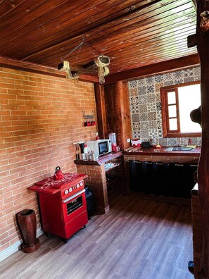 A rustic kitchen with a brick wall, wooden ceiling, and a window. - La Domita (Camanducaia)