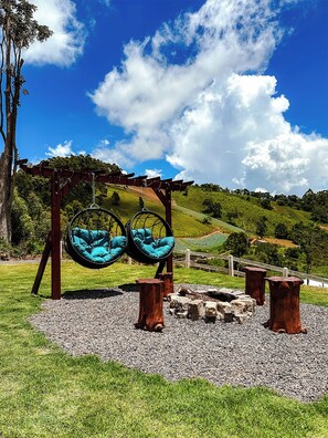 A swing set with two seats, a wooden pergola, and a gravel area with a wooden fence in the background. - La Domita (Camanducaia)