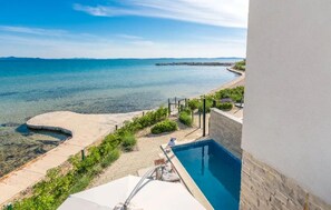 A pool with a clear view of the sea and a sandy beach area with steps leading to the pool. - Cozy home in Privlaka (Privlaka)
