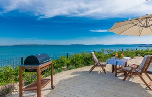 A patio with a grill, outdoor seating, and a view of the sea. - Cozy home in Privlaka (Privlaka)