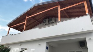 A modern building with a flat roof, wooden beams, and air conditioning units. - Nice apartment in Vrsi with WiFi (Vrsi)