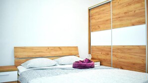 A bedroom with a wooden headboard, a bed with white bedding, a purple pillow, and a nightstand with a lamp. - Nice apartment in Vrsi with WiFi (Vrsi)