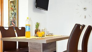 A dining area with a wooden table, four chairs, a bottle of orange juice, a pineapple, and a small decorative item. - Nice apartment in Vrsi with WiFi (Vrsi)