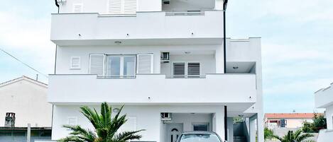 A modern two-story building with a car parked in front.