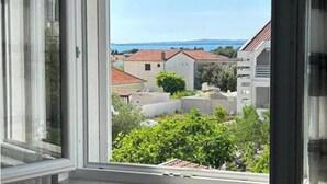 Blick aus einem Fenster auf ein Wohngebiet mit Häusern und einem klaren Himmel.