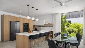 Cozinha moderna com ilha central, banquetas e mesa de jantar com cadeiras.