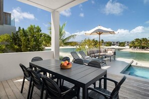 Ein überdachter Außenbereich mit Pool, Liegestühlen und einem Tisch mit Obst.
