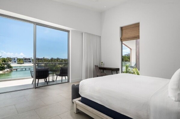 Ein modernes Hotelzimmer mit einem großen Bett, einem Schreibtisch und Blick auf Pool und Grünflächen.