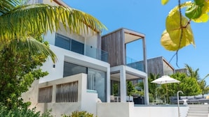 Ein modernes, zweistöckiges Haus mit großen Fenstern, einem Balkon und einem Poolbereich.
