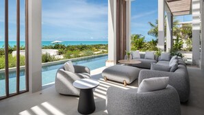 Un espace de vie extérieur moderne, doté d’une piscine, de coins salon et offrant une vue sur l’océan.