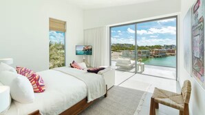 Une chambre moderne dotée d’un grand lit, d’une télévision et d’un balcon avec vue sur la piscine.